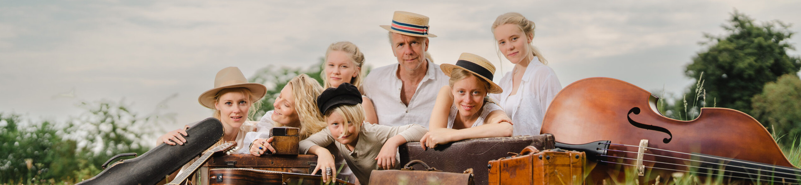 Die Miller Family mit ihren Instrumenten und Koffern auf einer Wiese